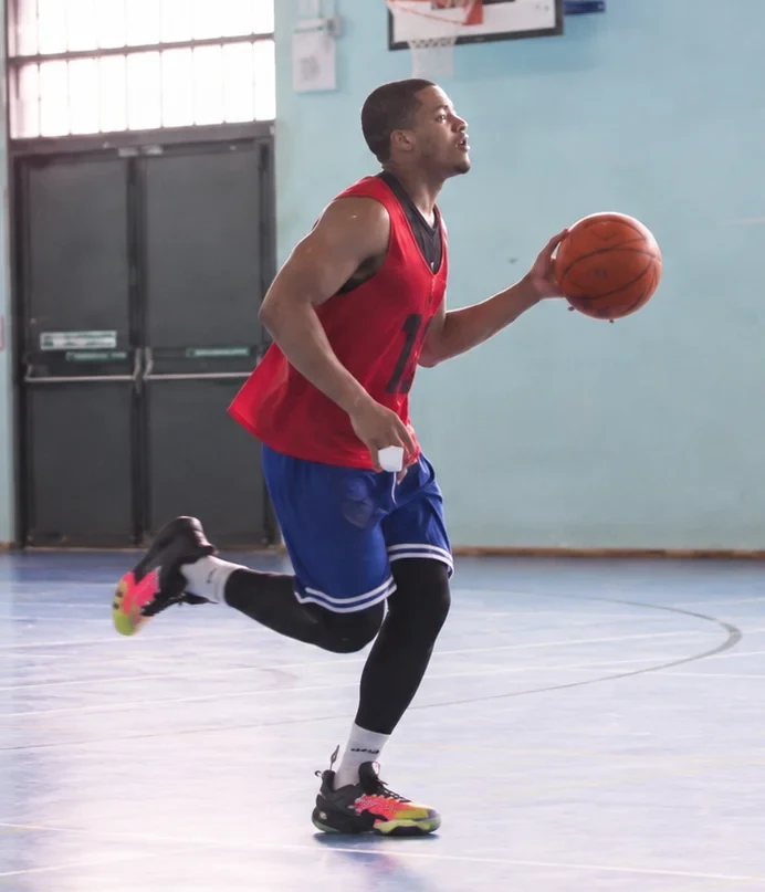 A young basketball player carrying the ball forward during a game